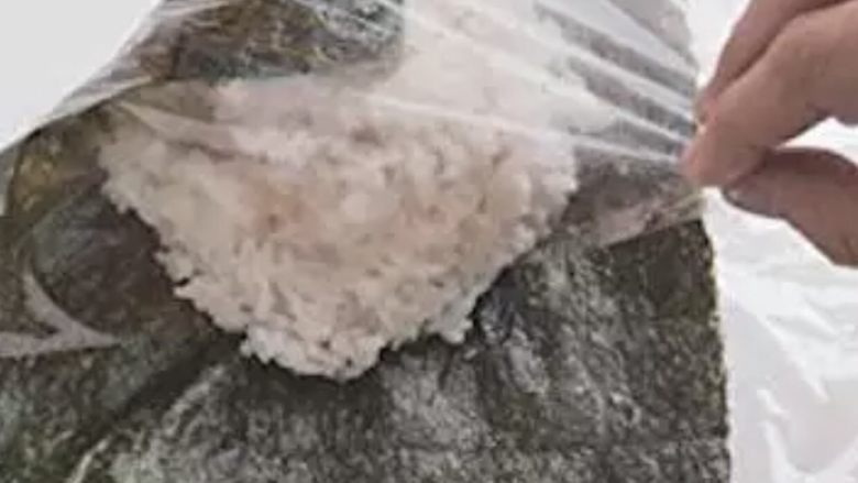 饭团便当,借保鲜膜把海苔的一个角拉过来,对角线的另个角也拉过来包好。同理再把另外两个角也包进来,用保险膜裹紧。