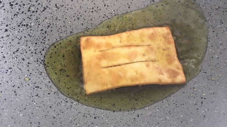 煎饼果子,热锅倒油,下入面皮,炸制金黄