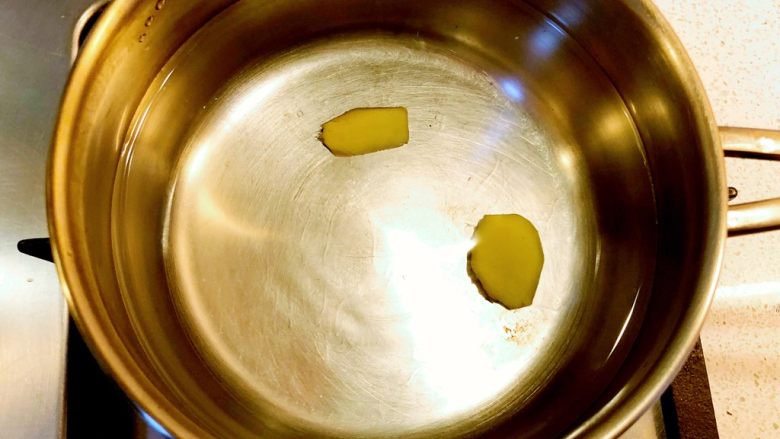 沙姜甜椒炒鱿鱼,锅中装水,下姜片,煮沸。