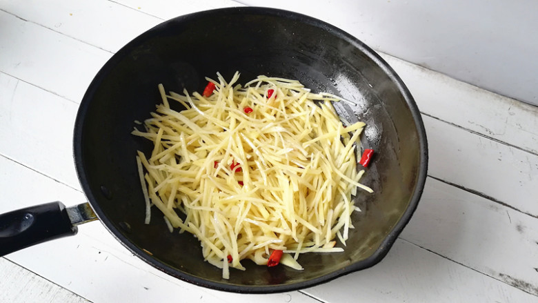 土豆丝炒芹菜,下入土豆丝大火翻炒,在淋入几滴<a style='color:red;display:inline-block;' href='/shicai/ 793'>米醋</a>翻炒,炒至土豆丝8成熟(如果炒制时太干,可以一边炒一边分次少淋些水)