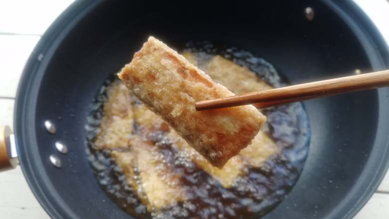 干炸带鱼,转中小火,将鱼段炸至外皮金黄、酥脆