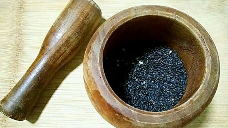 桂花黑芝麻汤圆(纯手工无油低糖版),将炒熟的黑芝麻倒入臼子中捣碎成粉。(有破壁机或料理机的亲们果断机打)