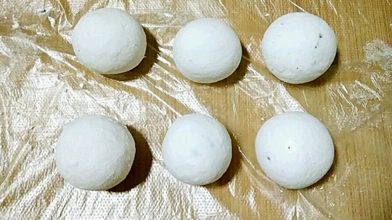桂花黑芝麻汤圆(纯手工无油低糖版),团好的汤圆放在保鲜膜上防粘。