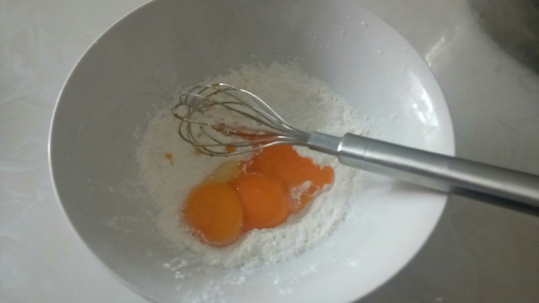 电饭锅蒸乳酪蛋糕,将蛋黄加入混合好的粉中,一定要马上搅拌均匀。