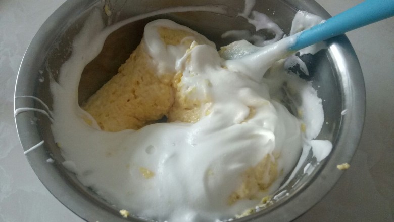 电饭锅蒸乳酪蛋糕,下加入1/2蛋白糊,用相切在翻拌的手法搅拌均匀,再加入1/2蛋白。