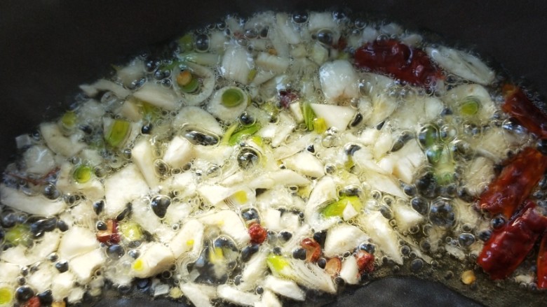 美味酸萝卜炒腊鸭心,起油锅,放干辣椒、花椒粒、蒜末小火煸出香味。