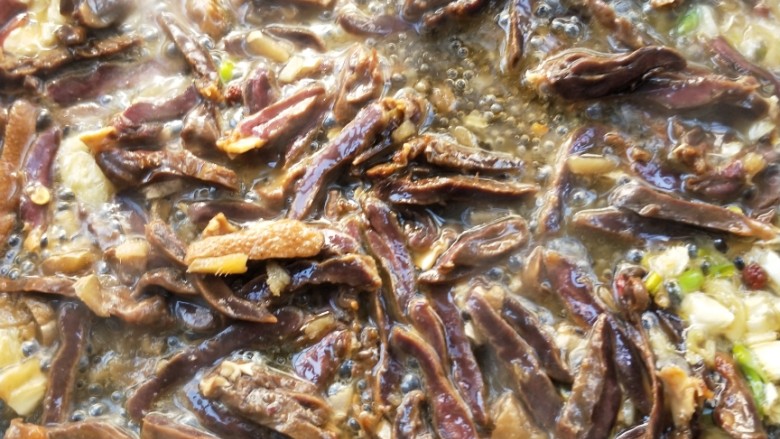 美味酸萝卜炒腊鸭心,倒入蒸熟的腊鸭心翻炒一下,接着把蒸腊鸭心的汁倒进去继续翻炒。