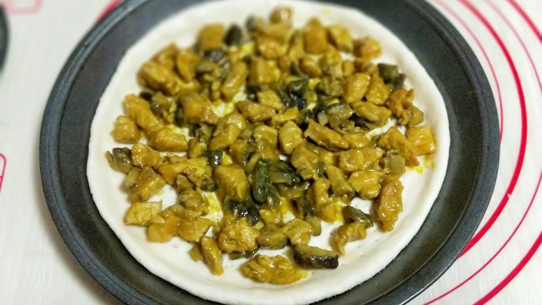 做饼+咖喱香菇鸡丁披萨饼,首先将披萨皮上面撒一层马苏里拉芝士,再将做好的咖喱鸡丁放在披萨皮上。