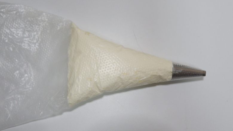 卡通喜洋洋麦芬杯奶油蛋糕,取适量打好的奶油装入裱花袋,不要全部装进去。