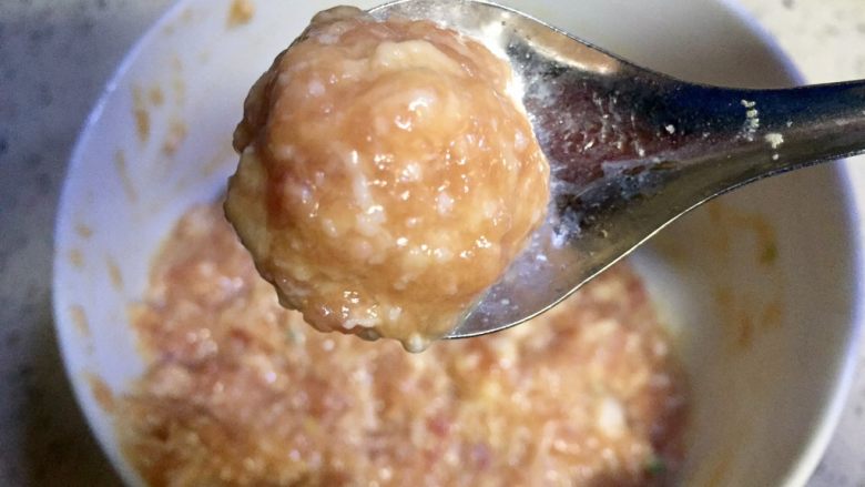 红绿相间番茄丸子豆尖汤,用勺子舀出丸子的形状,放在汤锅里,此时汤汁火力不可过猛只需保持微开状态即可,按此方法把肉馅都煮进汤里
