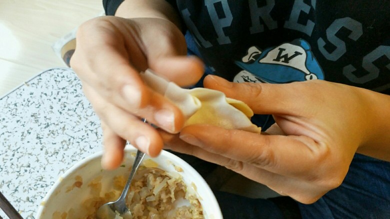 酸菜馅饺子,放入我这个小勺子一勺的馅儿,我个人很粗暴的两手使劲一捏边缘的饺皮就完事了。