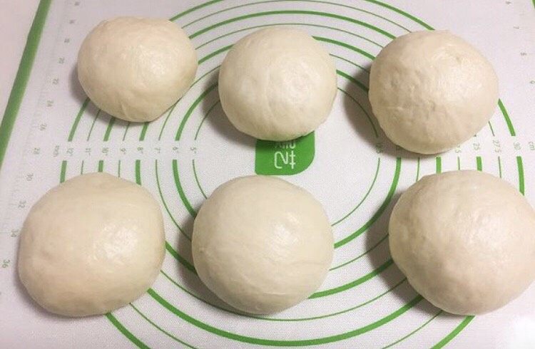 牛奶吐司(直接法),发酵好的面团轻拍排气,分成三个均匀的剂子后滚圆,盖保鲜膜静置10分钟。