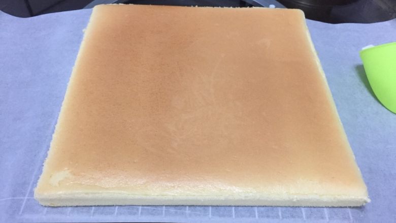 奶油蛋糕卷,烘烤结束马上拿出烤盘,把烤盘往台面上摔一下,震出内部的大气泡,连同油布移至晾网架上散热。
