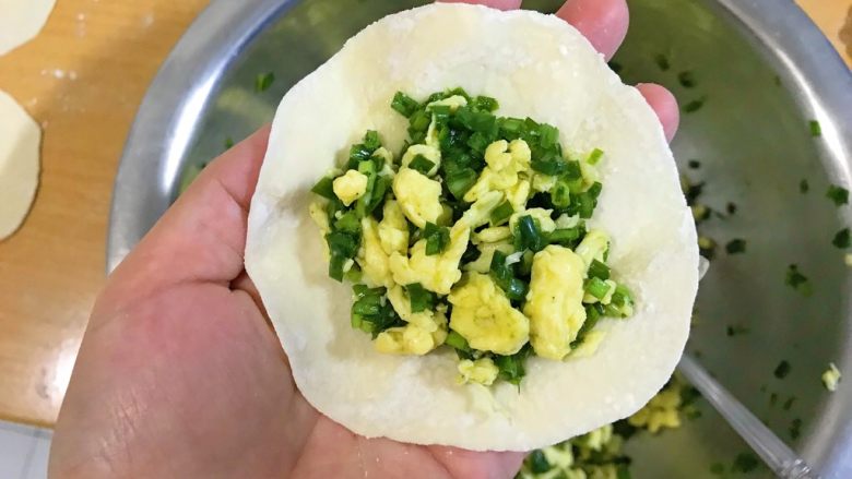 做饼+太阳盒子,用手托住一张面皮,放上馅料。