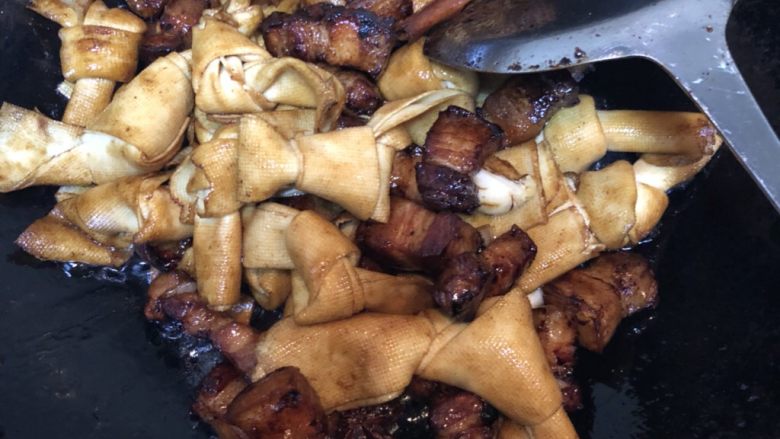 豆皮结烧肉,加入豆皮结翻炒一会,加入老抽,盐,八角,桂皮,加入适量水烧开,转中火盖锅炖20分钟