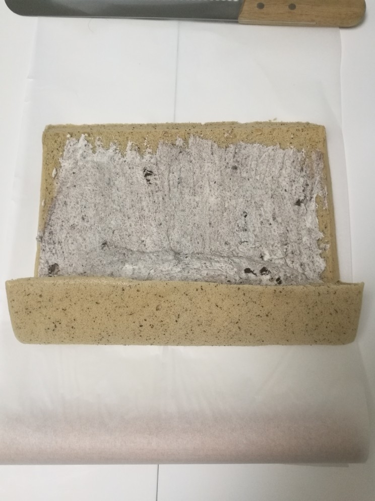无法忘怀奥利奥奶油红茶卷,用擀面杖卷起油纸,轻压蛋糕体一端