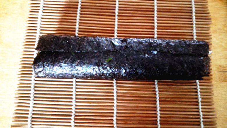 幸福的紫菜包饭,用寿司帘将其卷起,注意要卷得紧一些,这样切出来的寿司才漂亮,