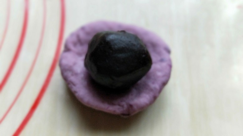 做年货-春节必备的紫薯豆沙包,取一块面团，包上豆沙，包紧，揉圆即可。