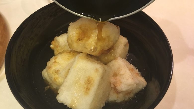 扬出豆腐,放进大碗里,淋上酱汁