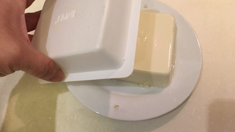 扬出豆腐,在豆腐盒上轻轻的敲几下,然后把盒子取掉