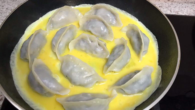 煎饺卧蛋,转动平底锅,让蛋液流动均匀,包裹住水饺