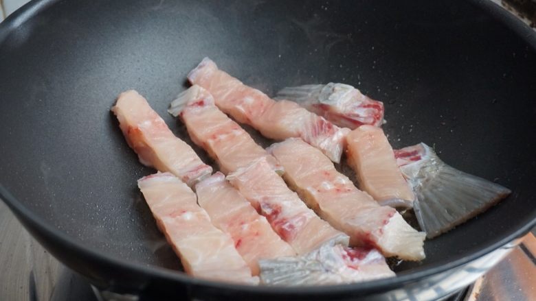 脆肉鲩鱼骨焖鸡,锅里加油、姜片,烧热后放入鱼骨