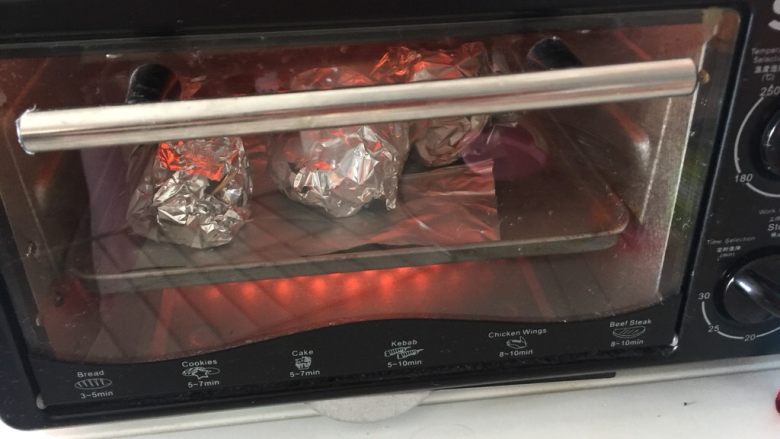 咖喱鸡腿包饭,然后放入预热好的烤箱中层,180摄氏度烤25分钟,中间取出翻面