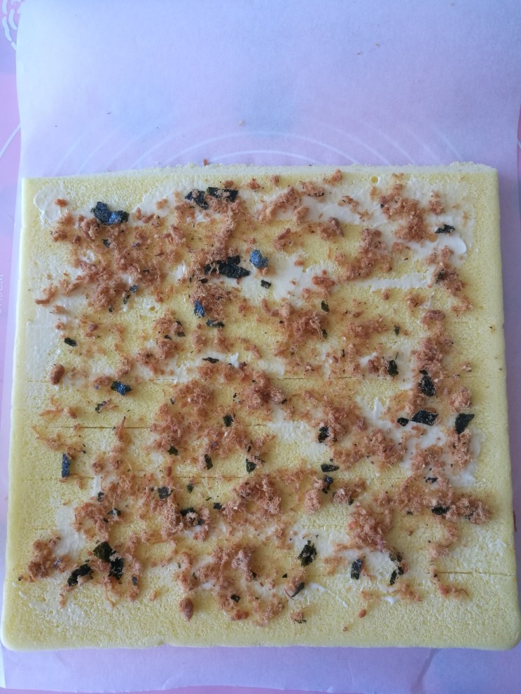 肉松蛋糕卷,10. 把蛋糕坯倒扣,远离自己的一边用刀斜切下一条,蛋糕表面用刀划几道,抹上沙拉酱,洒上肉松