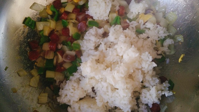 腊味菠萝炒饭,等洋葱,青椒,腊肠炒好以后。下入<a style='color:red;display:inline-block;' href='/shicai/ 507'>米饭</a>。