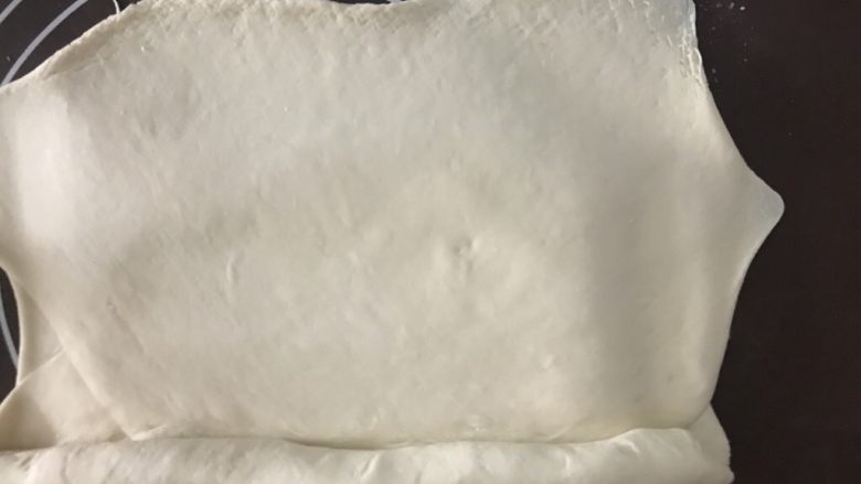 金牌牛肉煎包,把面皮擀至厚约0.5cm的大长方形,四周擀薄。沿一条长边卷起来,可以抹点<a style='color:red;display:inline-block;' href='/shicai/ 156925'>水</a>避免分层。