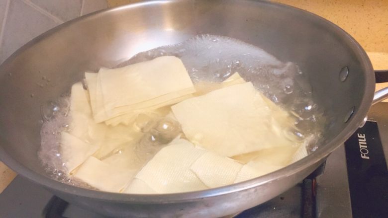 东北那旮沓的美食★京酱肉丝,这时候,水差不多开了。我们把干豆腐皮放进去烫煮2分钟。然后捞出来,沥干水分,备用。