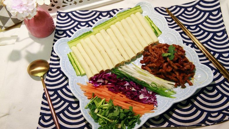 东北那旮沓的美食★京酱肉丝,一道菜,要怎么吃,还用佳儿说不?就是用干豆腐皮,包几根的肉丝,再加其他的配料,然后卷起来,一起吃进去。超满足的感觉!这道菜的口感就像开头我形容的一样。咸香,肉丝嫩滑,葱香加肉香香菜香还有其他蔬菜香配合,相得益彰。有点刺激口感,这种吃法,有点像北京烤鸭。我最爱之一就是烤鸭,所以京酱肉丝我也比较爱吃。饭桌上如果有这样一道需要自己动手去完成最终品尝时刻的有点DIY意思的菜,是很有意思的一件事情呢。年夜饭,也可以搭配这一道,你说呢?