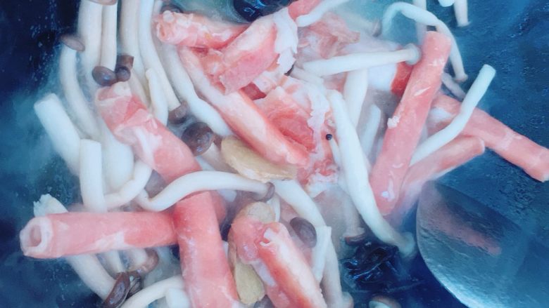 蟹味菇炒牛肉卷,把牛肉卷倒入锅里,翻炒一下,盖锅盖。