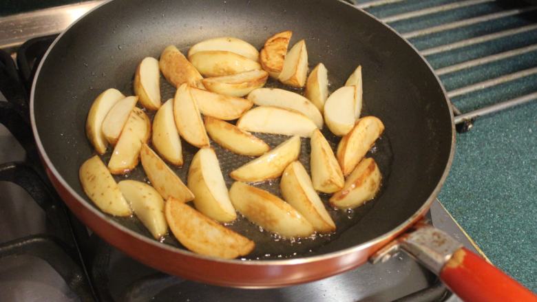 土豆炒蕈姑,趁油还没热放入土豆片,中小火,中间要稍稍翻面,煎到每面金黄。
