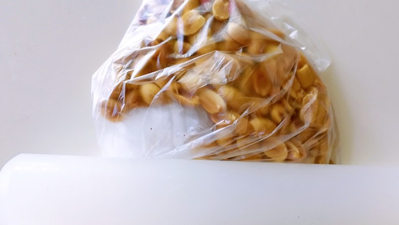 蛋黄花生酥~植物油版,取一把花生米去皮,放在保鲜膜里面,用擀面杖压碎