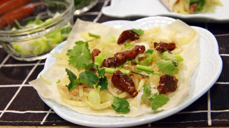 春饼卷土豆丝,吃的方法,还用佳儿告诉您不?就是把饼撕开,看,多薄的春饼呀!然后先铺一层土豆丝,然后放几块肉丝,再撒葱沫和香菜沫,可以根据自己的喜好增减配料用量,哈哈,自已动手,很有乐趣呢。