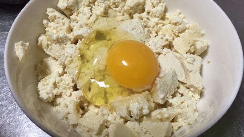 茼蒿炖豆腐虾,用勺子背压碎，打入一个鸡蛋搅拌均匀。