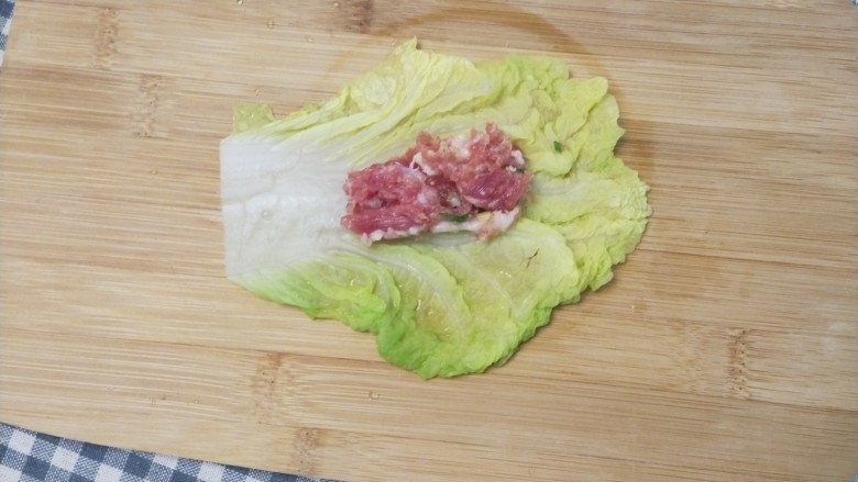 美味和颜值并存的白菜包肉,取一片白菜叶摊开,舀一勺肉末放到菜叶的中间