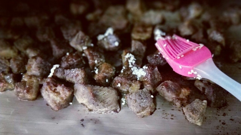 【健康零食】香烤孜然牛肉粒,取出刷上一层食用油。(食用油里面放了一把白芝麻)再次放入烤箱,180度烤10分钟。