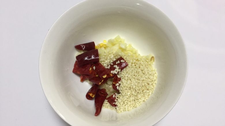 凉拌干丝金针菇,将蒜瓣切成蒜末(不用很细),辣椒切段去籽(喜欢很辣的就多加辣椒,或者直接加入油泼辣子也OK),芝麻全部放入一个小碗里