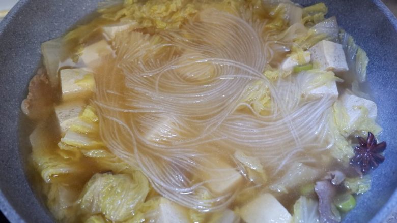 五花肉炖白菜冻豆腐,用锅铲压一下,让粉条完全浸泡在汤中。盖上盖子将所有材料煮熟。