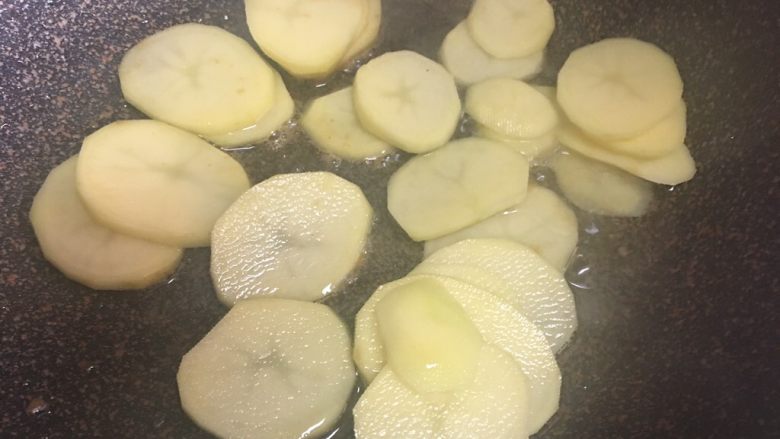 孜然土豆牛肉,煎土豆片，怕粘锅可以先撒点盐，然后土豆也更好先入一些盐分，因为牛肉腌制时也已经有些盐味了