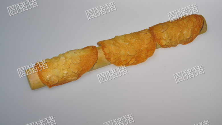 简单又美味的——杏仁瓦片酥,烤好的饼干乘着有些微热时,放在擀面杖上,折成弯形,放凉至变硬。