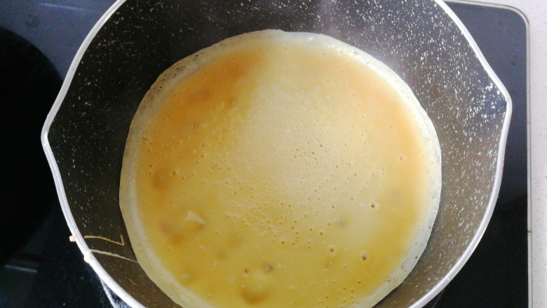 年菜~黄金福袋,不沾锅先刷一层薄薄的食用油,然后舀一勺蛋糊摊成薄薄的鸡蛋饼(不沾锅尽量选用小点的平底锅最好,我没有小号平底锅用小奶锅代替了)