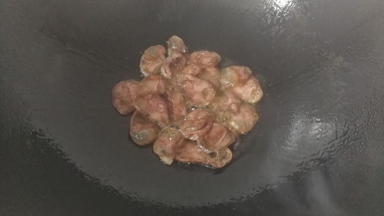 家常腊肠炒蒜苔,锅中入少许油,放入腊肠煸炒