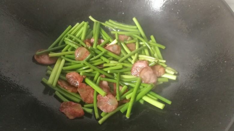 家常腊肠炒蒜苔,翻炒一会儿,调入少许盐继续翻炒,期间要适时点入清水翻炒