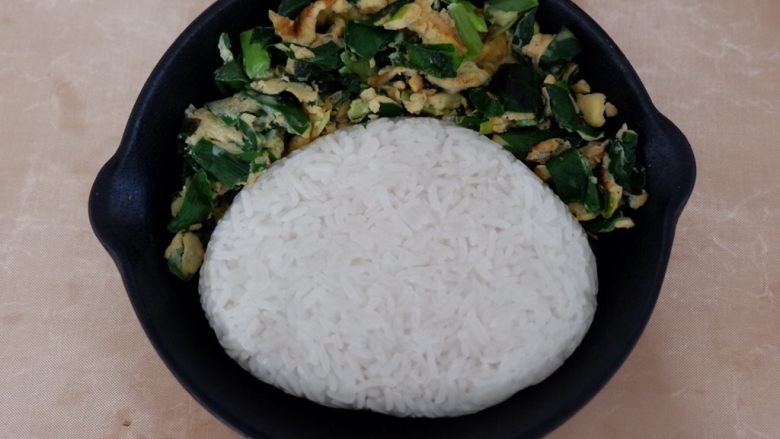 卡通早餐—韭菜鸡蛋娃娃饭,捏除脸的形状压扁,放到盘中调整成合适的大小。
