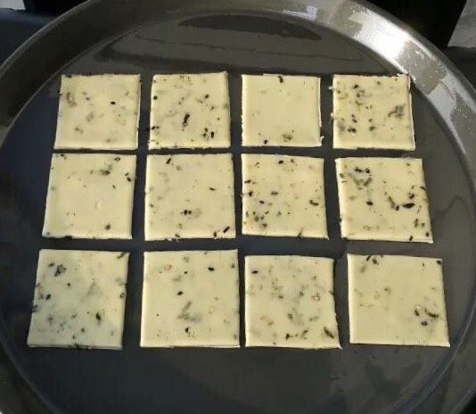 香葱海苔味苏打饼干,移动到烤盘上,用牙签在上面扎很多小眼儿。