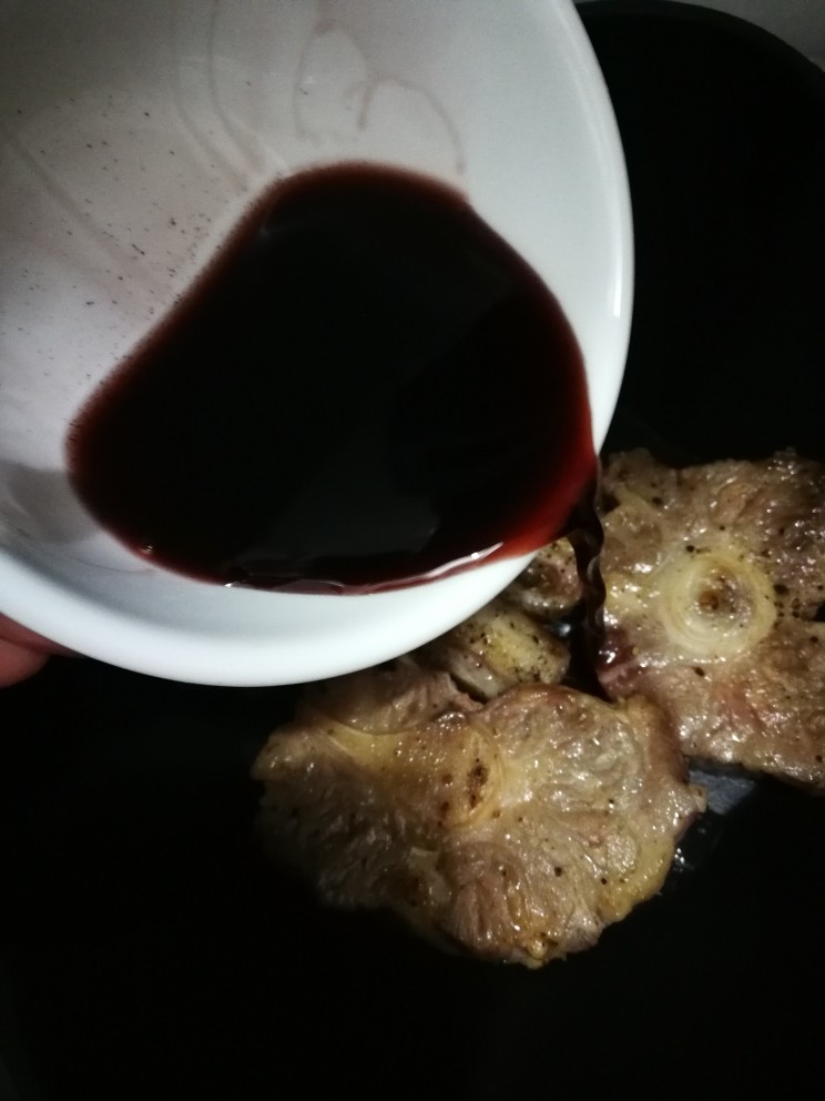 红酒炖牛尾,把煎好的牛尾移到汤锅里,大蒜不要。加入100nl左右的红酒。