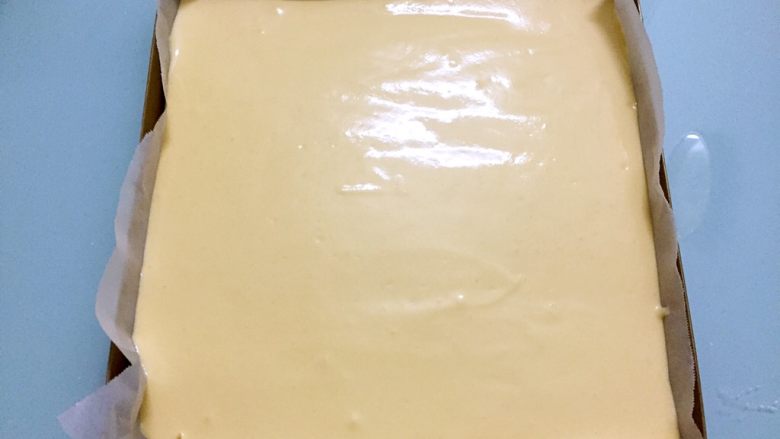 蛋糕盒子,烤箱上下火180度预热,烤盘铺上油纸,将蛋糕糊倒入,用刮刀抹平表面,拿起烤盘用力震一震,震出内部气泡